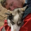 Personne embrassant un chien husky affectueusement